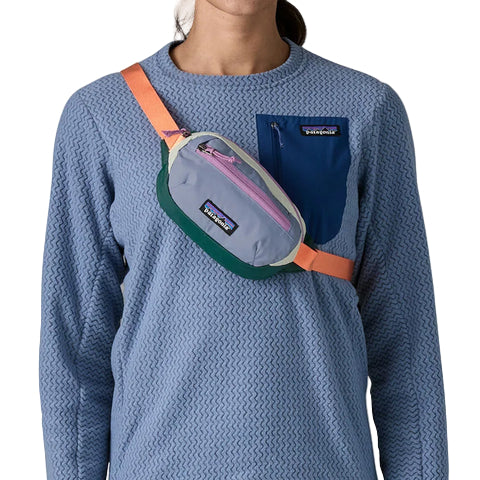 Person wearing a blue sweater with a Patagonia waist pack on a white background