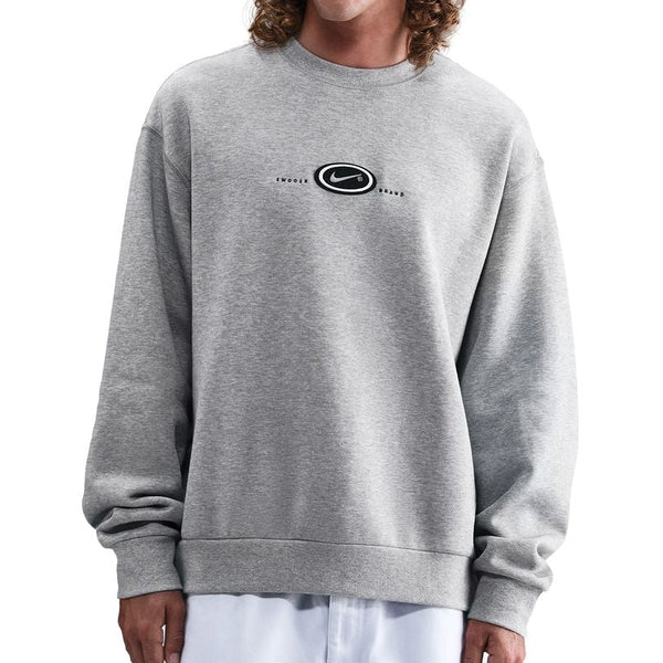 Man wearing a gray sweatshirt and white pants on a white background