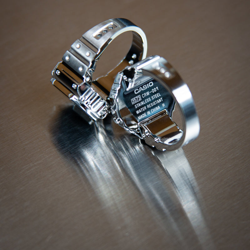 Silver Silver Casio crw001-1 ring watch on a reflective surface with a blurred background