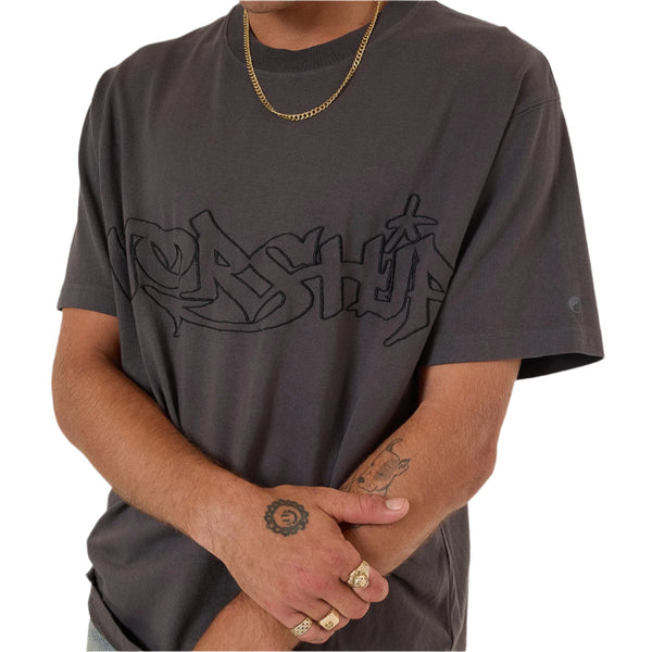 Man wearing a dark gray t-shirt with a logo, standing against a plain background