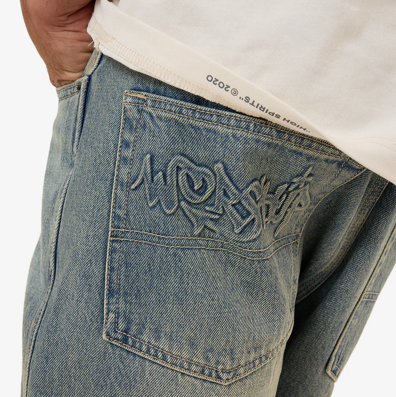Close-up of blue jeans with embroidery on a white background