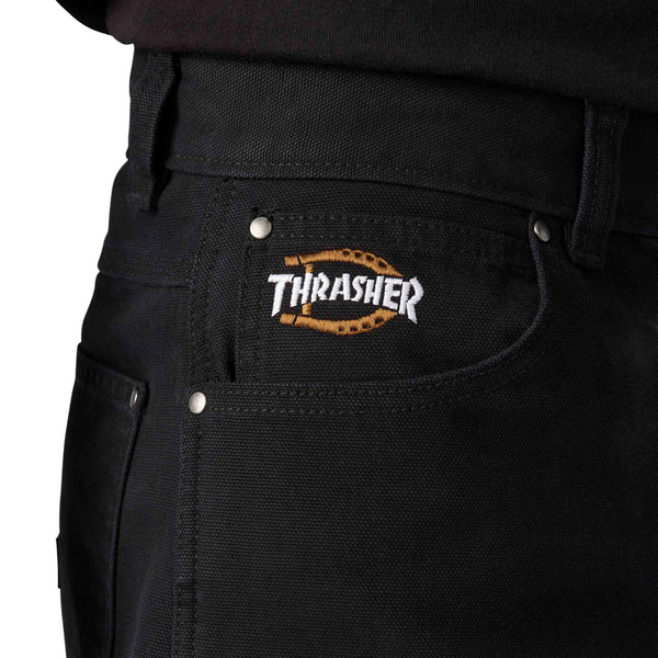 Black pants with a Thrasher logo on the pocket against a gray background