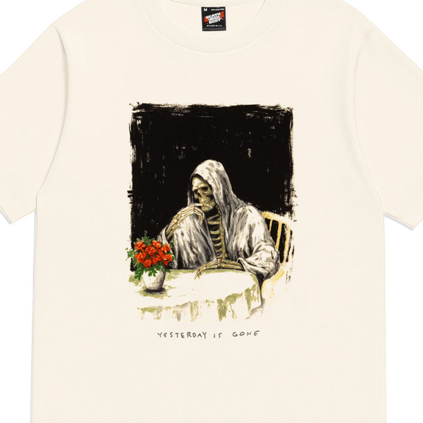 Beige t-shirt with a graphic of a person at a table with flowers on a white background